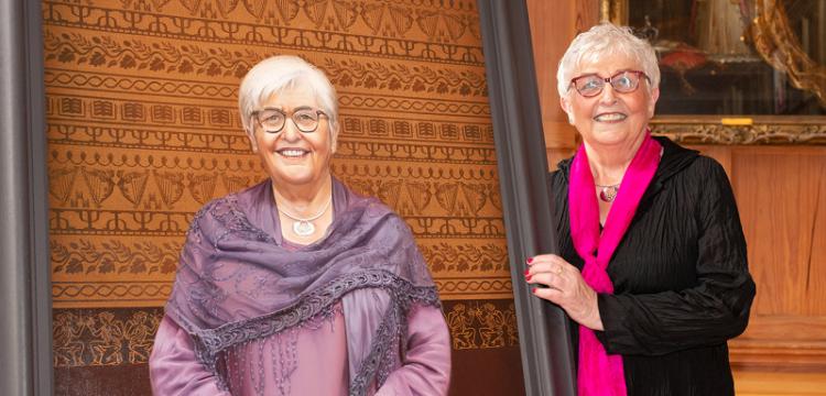 Prof Carol McGuinness posing beside her portrait in Queen's Great Hall