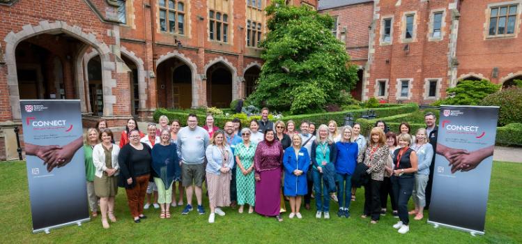 'Connect' staff network group shot between banners, Queen's quadrangle