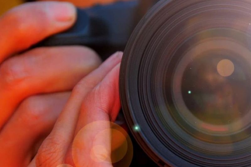 close-up looking into a camera lens while a person holds it and adjusts the zoom