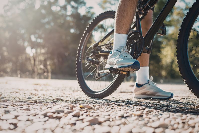 view from the ground of a man in trainers riding a stationary bicycle on a bright day