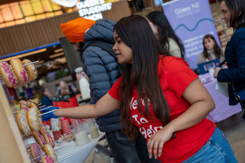 Student reaching for a decorated doughnut at a stall during a campus wellbeing event.