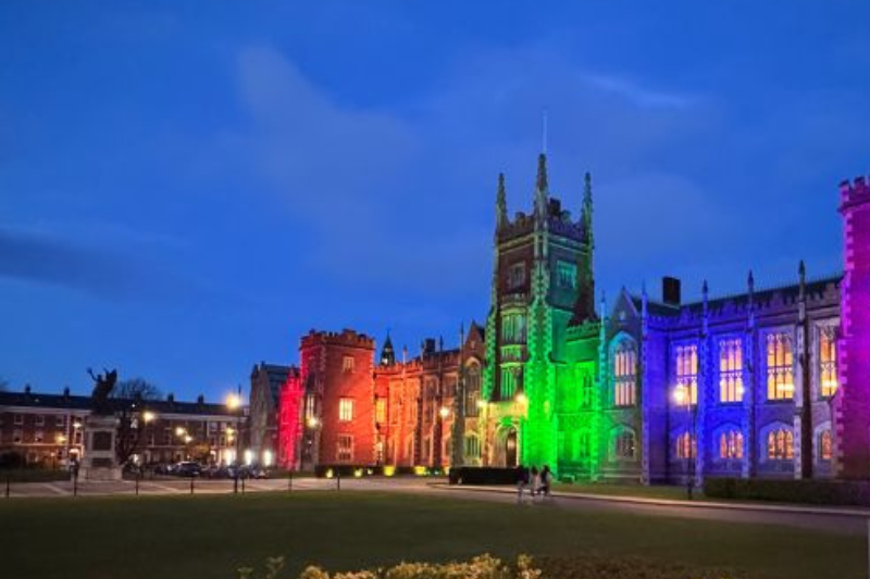 evening view of and old Victorian-era building illuminated in rainbow colours