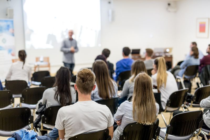 seated students listening to a lecture in a large hall