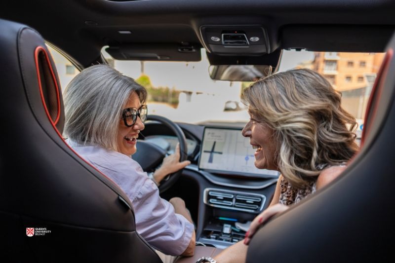 two mature women seated in a car sharing a laugh