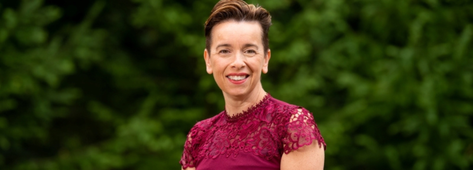 Woman standing and smiling, posing for a photo.