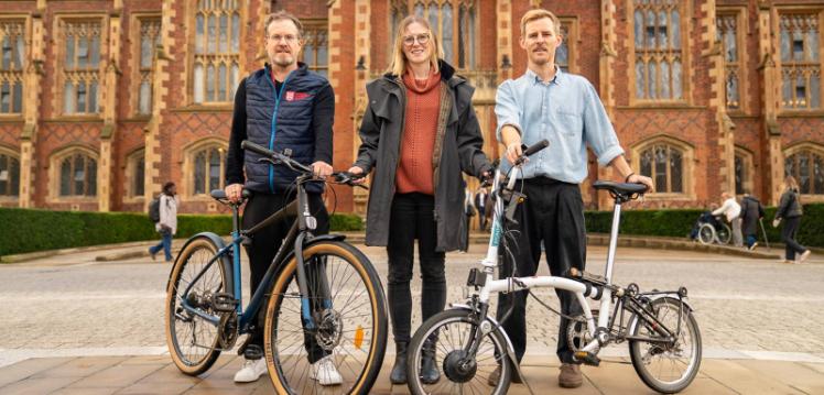 Three people pictured at front of Lanyon building with two bikes