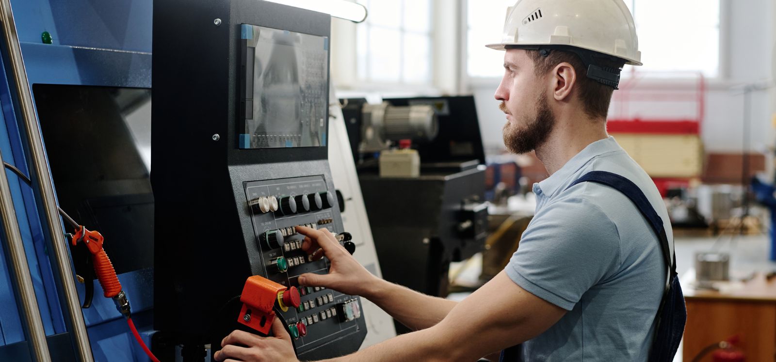 man wearing hard hat setting up a CNC machine in a factory setting