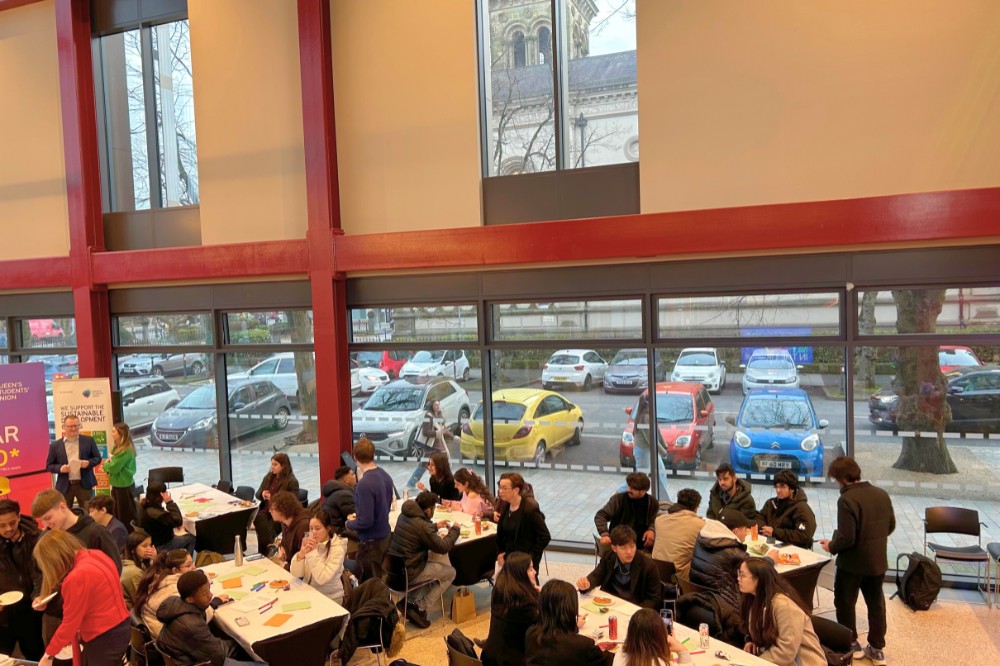 view from above of people standing, seated, chatting and taking food at an indoor event