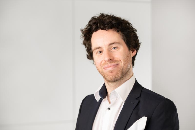 Headshot of a dark curly haired white male.