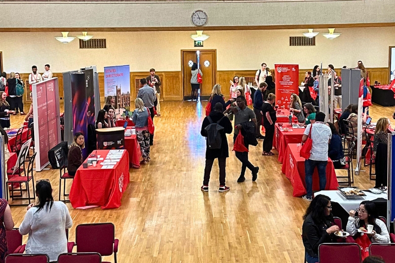 people milling around and chatting at stalls in a large, indoor event space